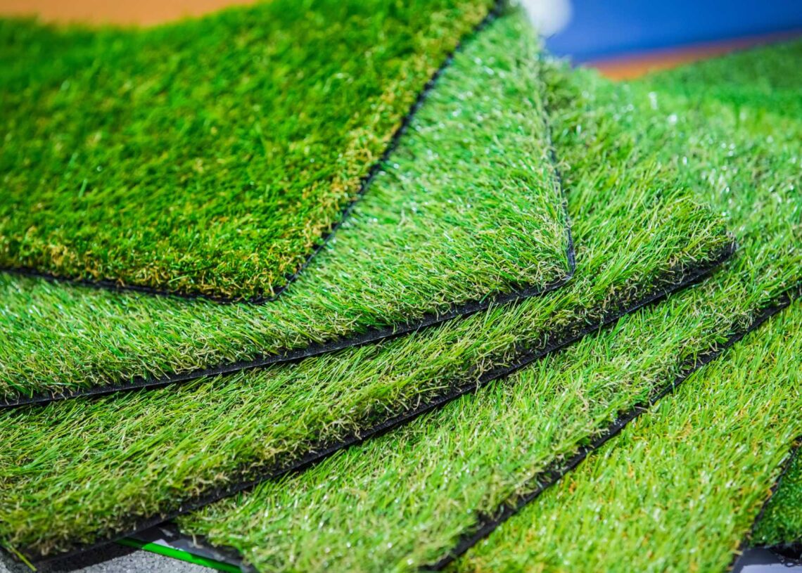 Multiple squares of artificial turf stacked on each other to show various styles and textures of turf.