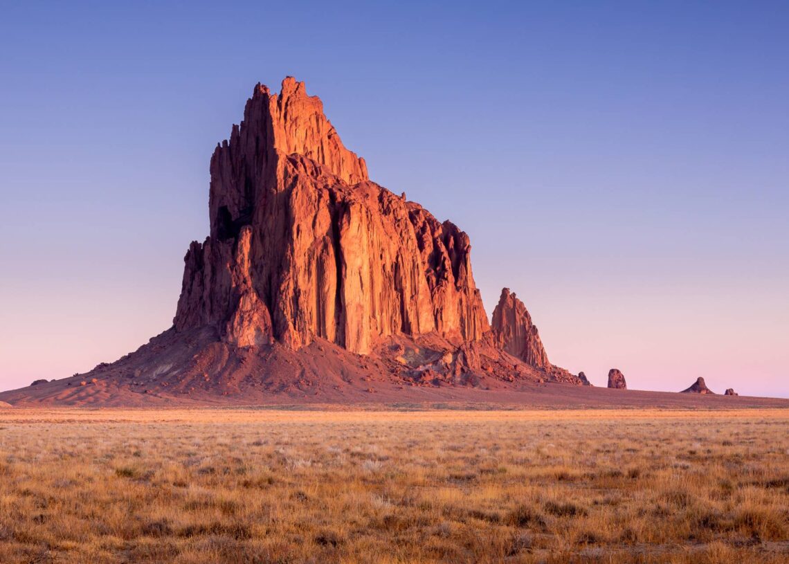 An incredibly beautiful shot of the Shiprock natural rock formation in New Mexico bathed in the golden sun.