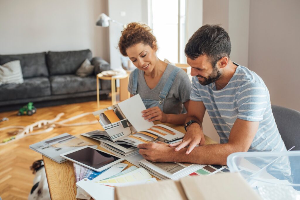 A couple looking over details for a home renovation and making plans together. They are both smiling.