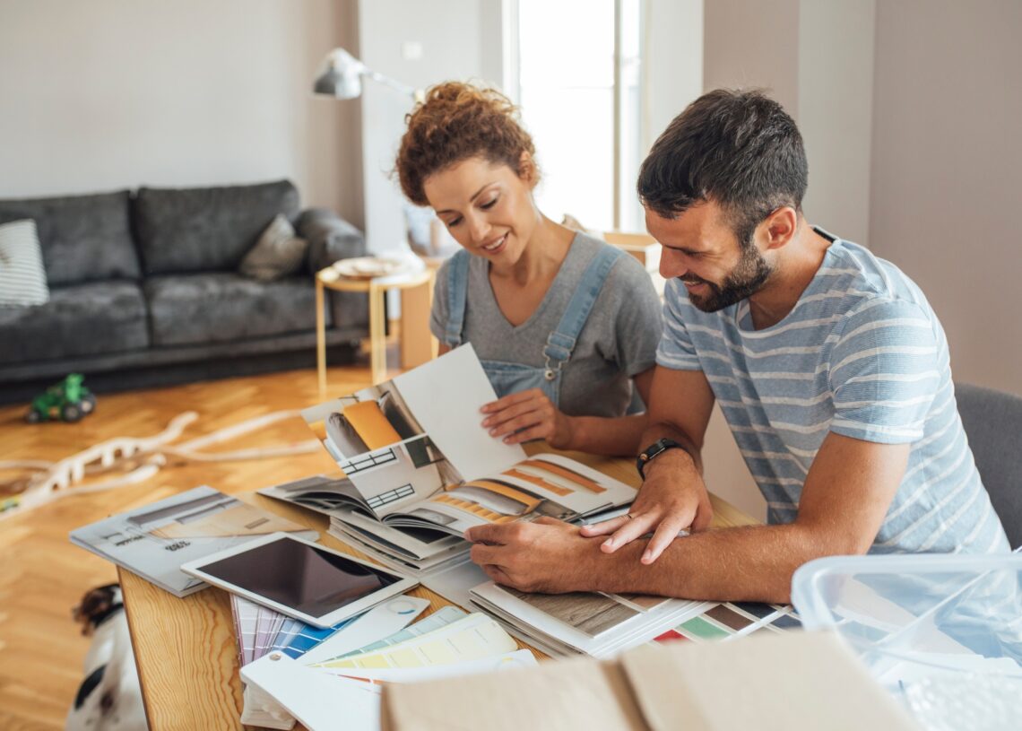A couple looking over details for a home renovation and making plans together. They are both smiling.