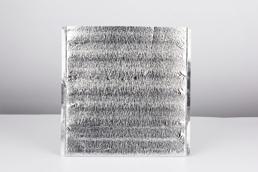 A silver thermal pouch sits alone on a white and gray background. The top of the bag is cut open.