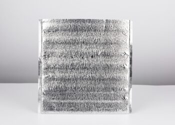 A silver thermal pouch sits alone on a white and gray background. The top of the bag is cut open.