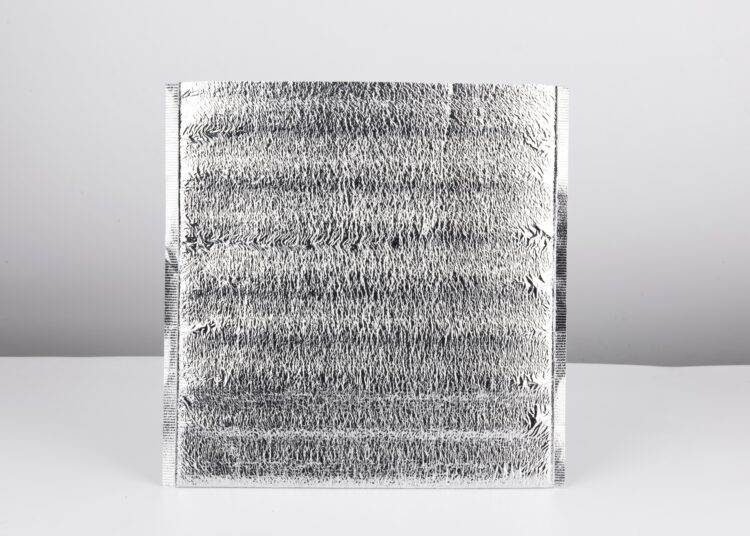 A silver thermal pouch sits alone on a white and gray background. The top of the bag is cut open.