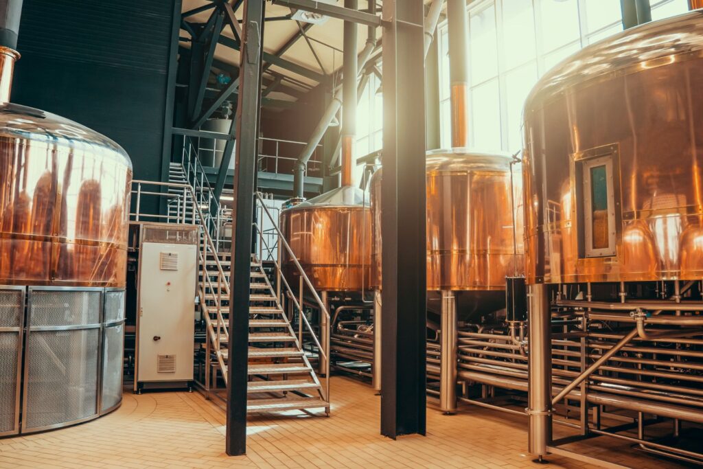 A large brewery facility space featuring large, round copper storage tanks for fermentation and maturation.