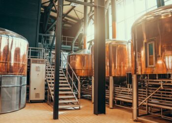 A large brewery facility space featuring large, round copper storage tanks for fermentation and maturation.