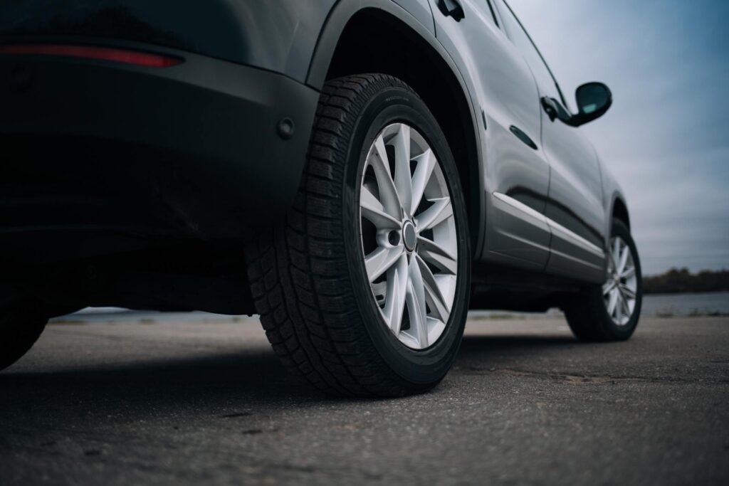 The bottom part of a parked black SUV. The vehicle's tires are clean and shiny, with no visible problems.