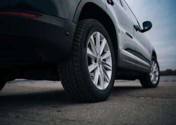The bottom part of a parked black SUV. The vehicle's tires are clean and shiny, with no visible problems.