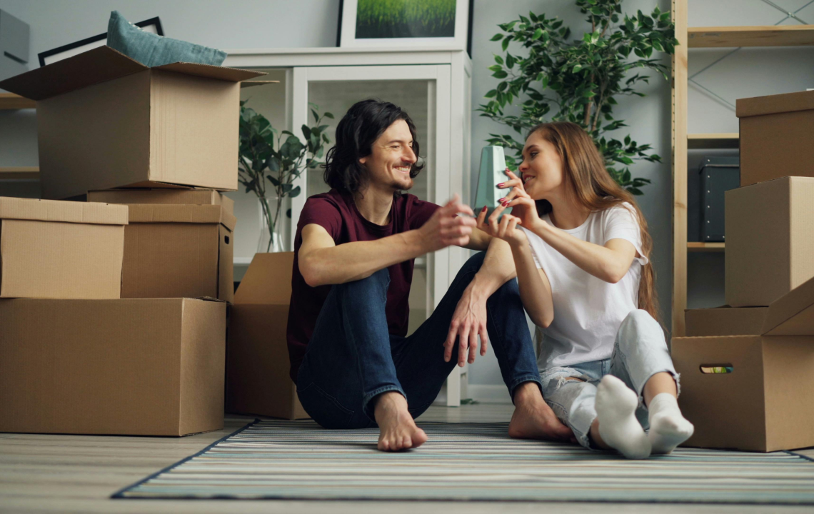 Smiling Couple Sitting on Floor in House