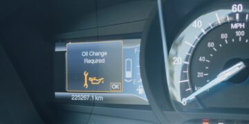 A car dashboard showing an illuminated “Oil Change Required” warning with a wrench icon next to the speedometer.