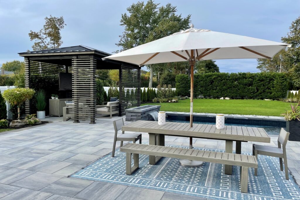 An outdoor living space with a dining area, a covered seating area, a pool with a water feature, and open yard space.