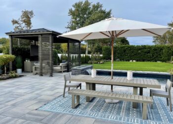 An outdoor living space with a dining area, a covered seating area, a pool with a water feature, and open yard space.