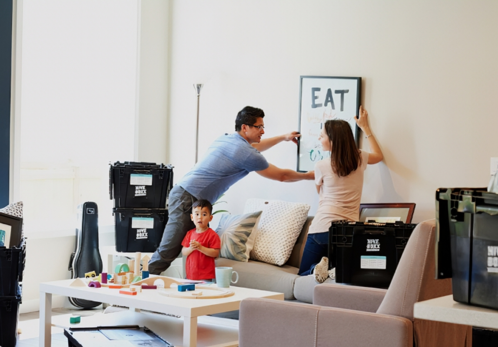 A young family carrying moving boxes into a new home