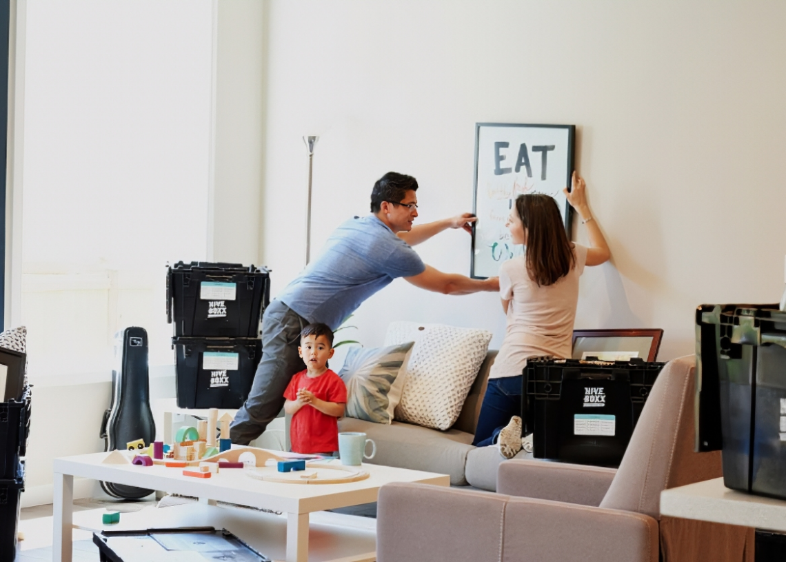 A young family carrying moving boxes into a new home