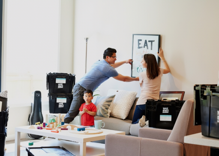 A young family carrying moving boxes into a new home