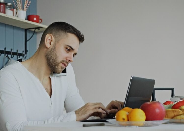 A person placing an online order on a laptop at a kitchen table
